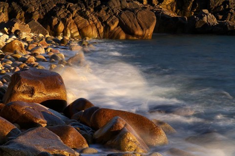 Stones, pebbles, pebbles, washed by water, waves, spray, motion effect, long exposure, evening