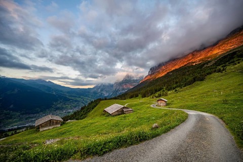 Road, alpine huts and alpine meadows, mountain landscape at sunset, summit of the Wetterhorn in the