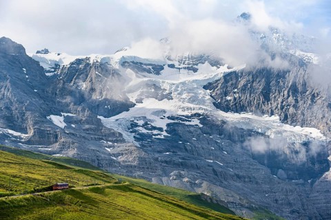 Jungfrau Railway to Jungfraujoch runs through green meadows, above the Kleine Scheidegg stop, rack