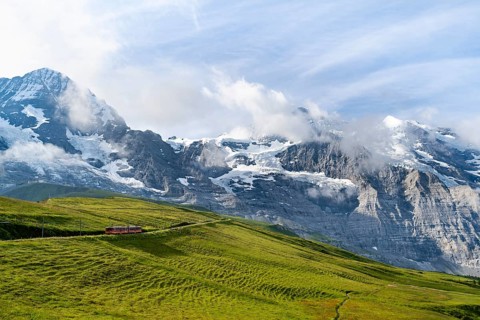 Jungfrau Railway to Jungfraujoch runs through green meadows, above the Kleine Scheidegg stop, rack