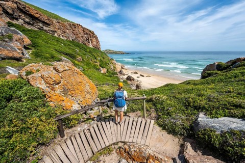 Young pretty woman wearing dress off coast and sea at Robberg Nature Reserve, Plettenberg Bay,