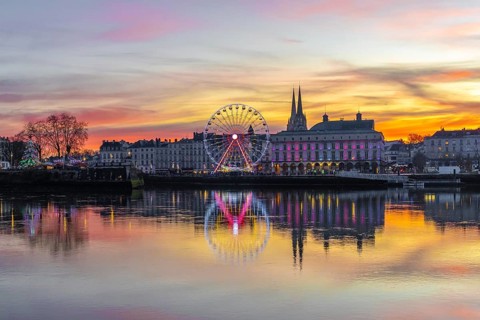 Bayonne skyline glowing at sunset with festive lights, ferris wheel and cathedral reflected in the