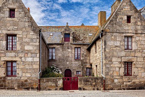 Historic stone house with gabled roofs and old bricks under a blue sky, historic stone house in