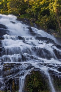 Mae Ya waterfall with cascading flowing water surrounded by lush tropical vegetation, near Doi