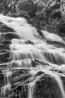 Mae Ya waterfall with cascading flowing water framed by lush tropical vegetation, black and white