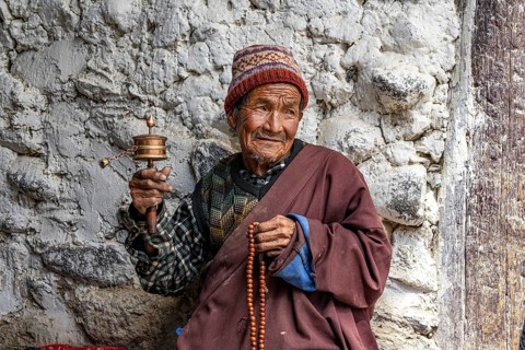 Elderly man with Buddhist stone mill and prayer necklace, Mala, in traditional dress, Lo Manthang,