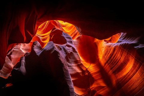 Slot canyon walls showing sunlit sandstone formations with vibrant orange, red, and purple hues