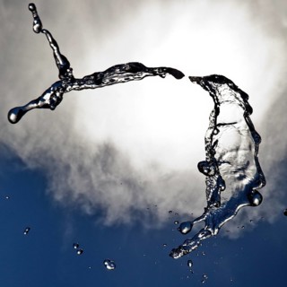 Water frozen as a result of short exposure moving in the backlight in front of the sky