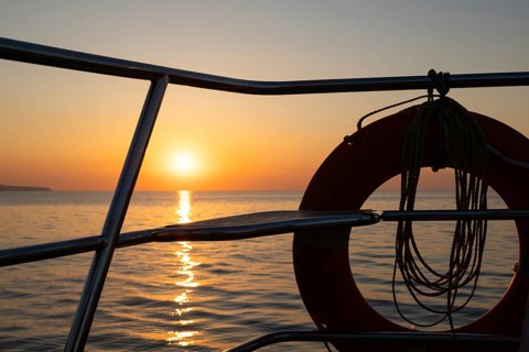 View of Mediterranean Sea and setting sun from a sailing ship through lifebuoy, Strait of Messina,