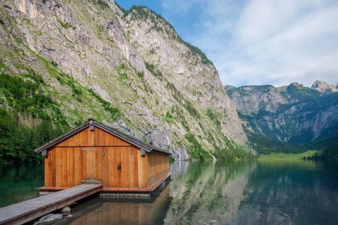 Scenic view of a rustic wooden boathouse and dock on the emerald waters of Obersee lake in