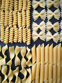 The texture of four types of dry pasta: tagliatelle, farfalle, penne and fusilli.Close-up. Top view