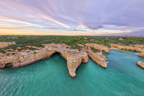 Drone sunset view of Arco de Albandeira at Praia de Albandeira in Algarve, Portugal, with limestone