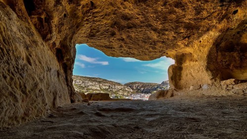 Sky changed, Neolithic caves, former hippie paradise, view from a reddish brown cave of the