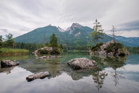 Wide angle view of the transparent water at Hintersee lake featuring rocky islands and the Hoher