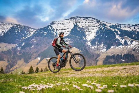 Pretty mid age woman riding her electric mountain bike in early springtime in the Allgau mountains,