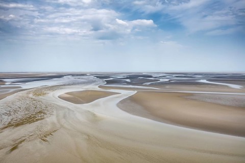View from the rocky island, monastery island of Le Mont Saint Michel onto a wide mudflat landscape