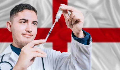 Doctor holding syringe on England flag background. Medical professional holding syringe with