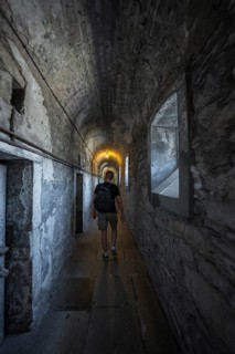 Person with backpack in a gloomy stone corridor, Kilmainham Gaol Prison, Dublin, Ireland