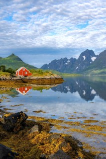 Red fishing hut on the shore, Rorbuer hut, picturesque fjord landscape at Raftsund fjord, mountains