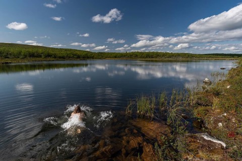 Woman jumping into a lake, near Utsjoki or Ohcejohka, Lapland, Finland