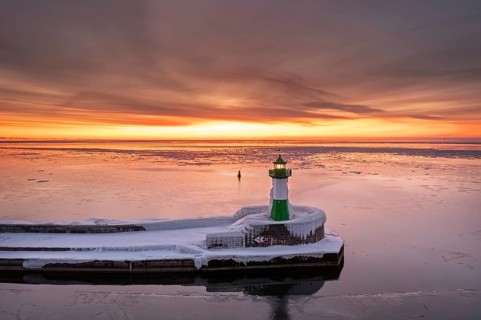 Ice covered Molenfeuer, frozen lighthouse, pier light on mole in Sassnitz harbour at sunrise in