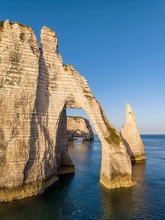 Aerial view of the Porte d'Aval rock formation shortly after sunrise, well-known landmark on the