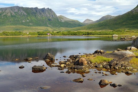 Rocks on the shore of a quiet lake with mountains in the background, Andoeya, Nordland, Vesteralen,