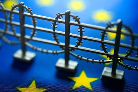 Miniature fence with barbed wire on EU flag, symbolic photo of European asylum reform +++ editorial