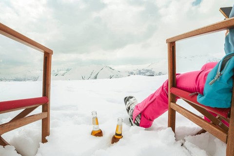 Couple relax sit on chairs in snowy ski resort with beer bottle, concept of leisure, winter