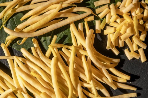 Sliced and whole yellow beans on leaves