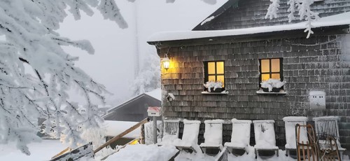 Snowy hut, Kösseinehaus with warm lights in a winter landscape, hiking in winter, Fichtelgebirge