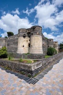 Monumental castle complex from the 13th century with distinctive tower architecture, nestled in a
