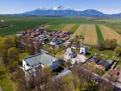 Aerial view of the village with a castle and tower surrounded by green fields and mountains, aerial