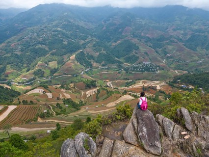 Aerial view of a woman with a pink rucksack sitting on The Dinosaur Backbone (S?ng Lung Kh?ng
