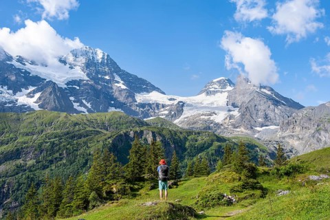 Hikers in front of picturesque mountain landscape with Breithorn and Tschingelhorn mountain peaks,