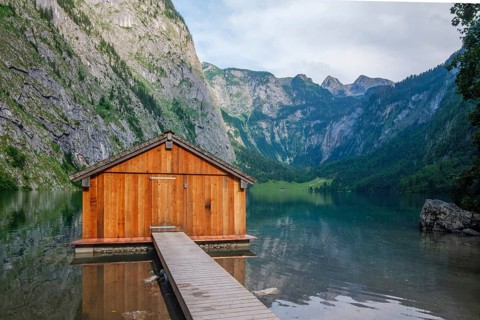 Iconic wooden boathouse on the shore of Obersee lake with a stunning backdrop of the high Alps in