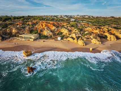 Drone view of turquoise water, breaking waves, and sand at Praia de Sao Rafael beach in Algarve