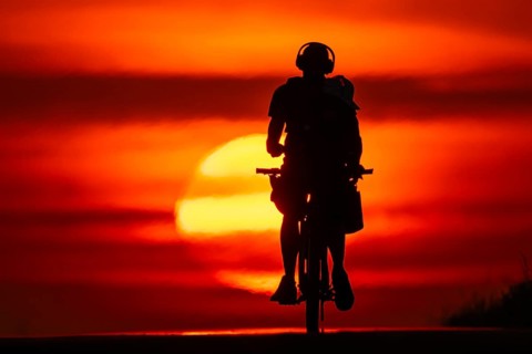 A cyclist rides towards the rising sun on a dirt road near Frankfurt am Main, Frankfurt am Main,