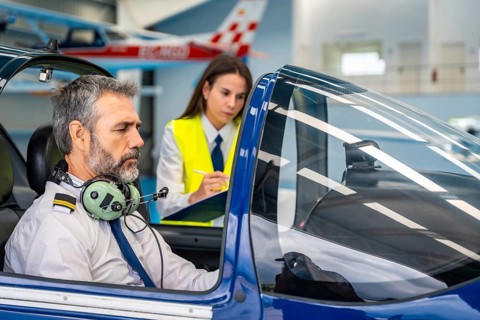 Experienced male pilot instructor providing flight training to a young female student, reviewing