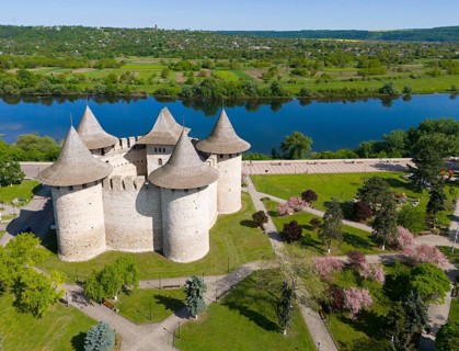 Castle with tall towers in a green landscape next to a river, aerial view, Soroca Fortress,