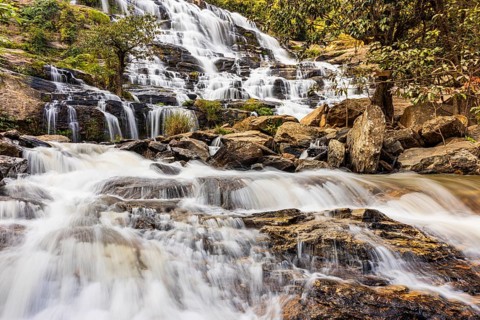 Mae Ya waterfall with cascading flowing water surrounded by lush tropical vegetation, near Doi