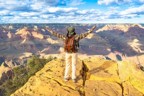 Person with outstretched arms expressing freedom and adventure while standing on a rocky outlook,