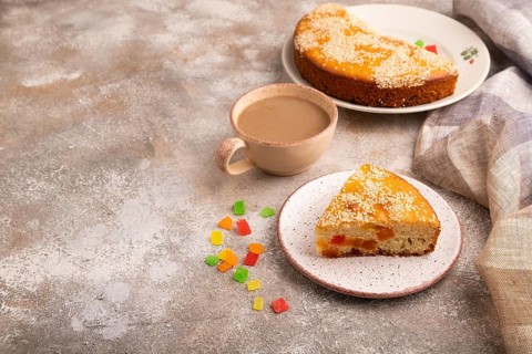 Pie with candied fruit, cup of coffee, on brown concrete background with linen beige textile, copy