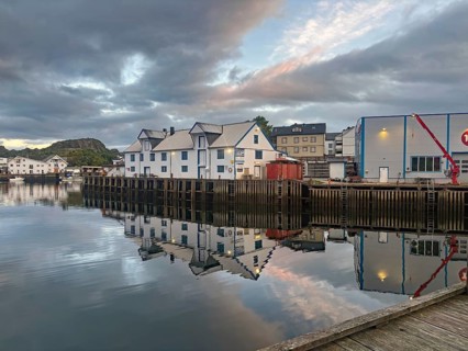 Quiet harbor with white wooden houses and calm water reflections at dusk, midnight, cable vag,