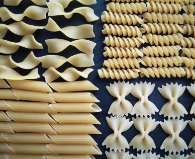 The texture of four types of pasta: tagliatelle, farfalle, penne and fusilli.Close-up. Top view.