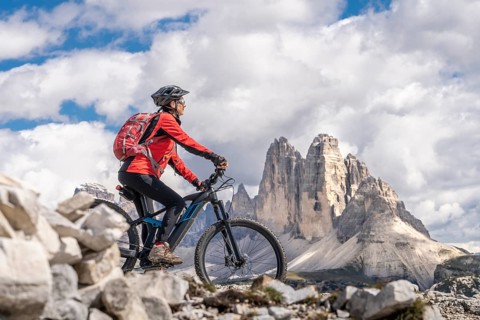Senior woman with electric mountain bike below the famous Three Peaks in the Dolomites, Toblach,