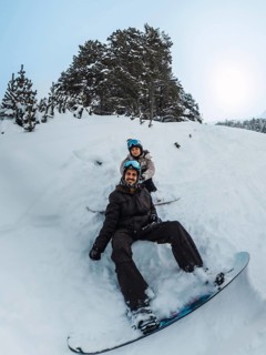 Two friends sharing a joyful snowboarding moment on a snowy mountain slope, wearing winter gear and