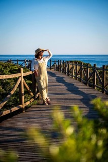 Woman, 54, wearing a sunhat looking at the sun at the Dunas de Artola, Spain