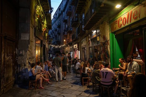 People enjoy a cozy evening in busy street cafes, atmospheric lighting, Palermo, Sicily, Italy