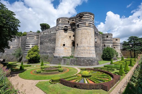 Monumental castle complex from the 13th century with distinctive tower architecture, nestled in a